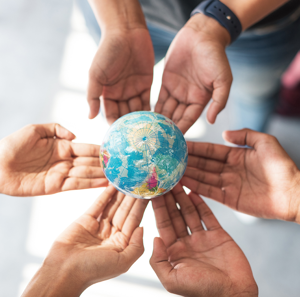 Six hands holding a small globe